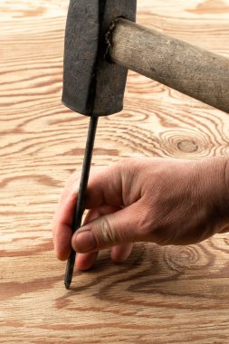 Adam hasarlı bir yüzeye çivi çakıyor.