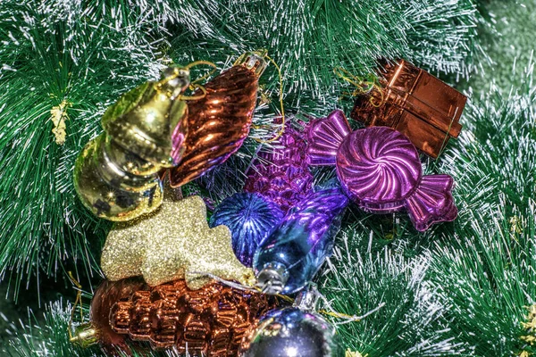 Multicolored Christmas toys lie on the artificial green spruce branches — Stock Photo, Image