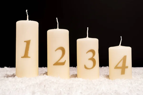 四支蜡烛在雪与数字一 三和四 黑色背景 — 图库照片