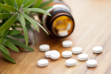 Tabletler ile homeopatik ilaç-ahşap masada tabletlerle şişe