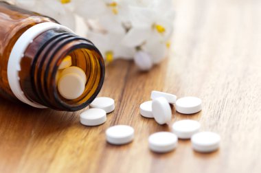 Tabletler ile homeopatik ilaç-tablet ile şişe ve ahşap masada Yasemin bir dal