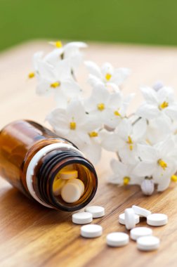 Tabletler ile homeopatik ilaç-tablet ile şişe ve ahşap masada Yasemin bir dal