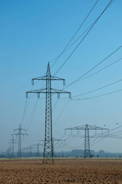 High voltage lines in front of a bright blue sky