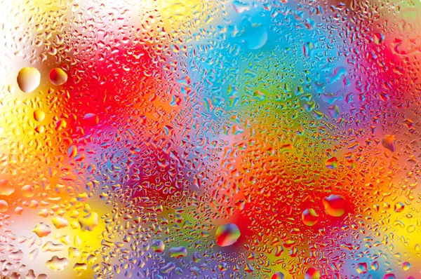 Renkli arka plan, ana renk mavi, dar alan derinliği cam tabakta su damlası