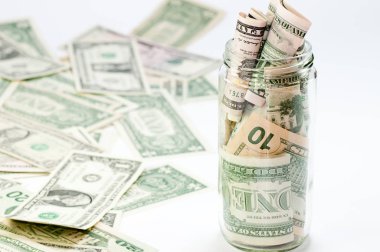 Birçok dolar faturaları ve yanında birçok banknot ile bir bardak