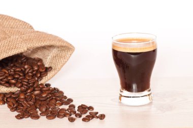Bir bardak taze sıcak espresso ve kavrulmuş Kahvenin yanında
