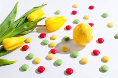 Sarı Paskalya yortusu yumurta sarı laleler ve renkli çikolata fasulye ile