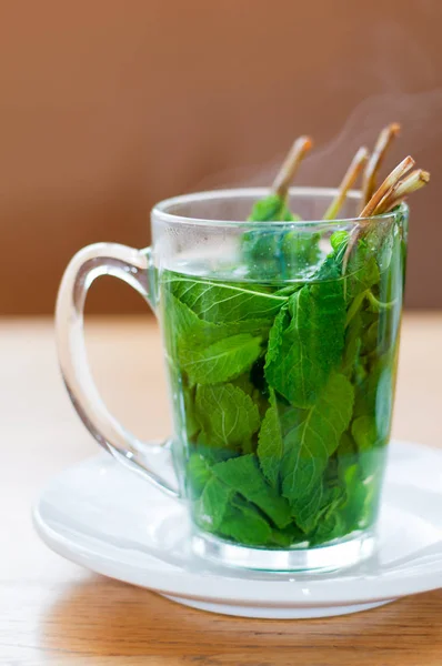 A cup of tea with fresh peppermint leaves