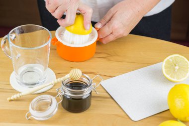 Kadın taze sıcak limonlu çay yapmak için limon meyve suyu sıkmak