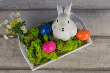 Paskalya sepeti ile birçok renkli Paskalya yumurtaları ve bir beyaz tavşan dekorasyon, üstten görünüm