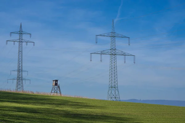 High voltage line in front of bright blue sky, vertical with copy space