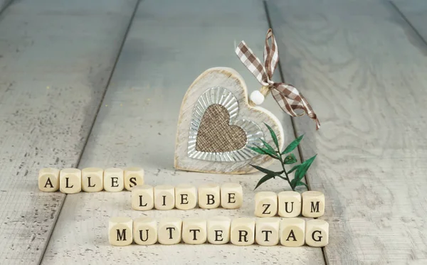 The German words for all Love for Mother\'s Day in letters with heart of wood behind it