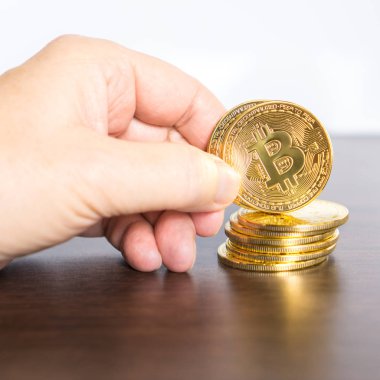 El parmakları arasında kare tutan altın bitcoin