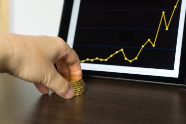 Bir kaç bitcoins, bir grafik ile bir tablet arka planda tutan el