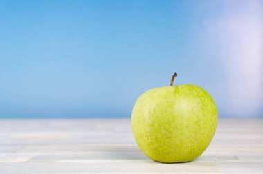 Ahşap masa mavi gökyüzü arka plan ile yeşil elma meyve 