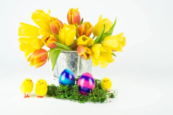 A bouquet of red and yellow tulips with two Easter eggs and three little chicks