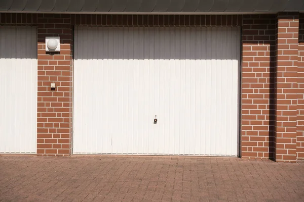 A white garage door with brick wall