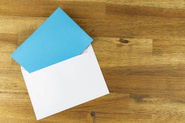 Mavi boş kağıt, ahşap arka plan beyaz zarfı