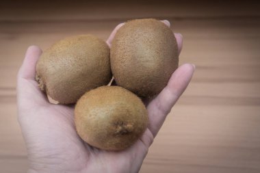 Elinde tutan üç Kivi Meyve