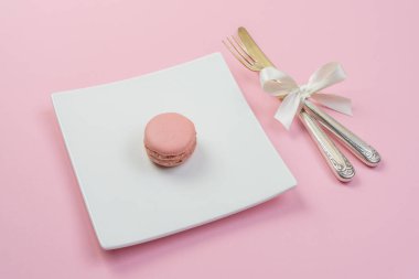 Pembe macarons ve gümüş çatal bıçak takımı ile beyaz plaka
