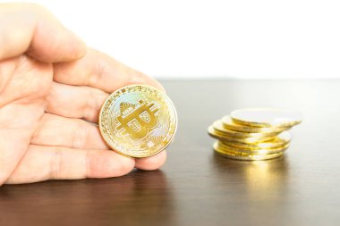 Bitcoins yığını ve elinde tutan bir bitcoin