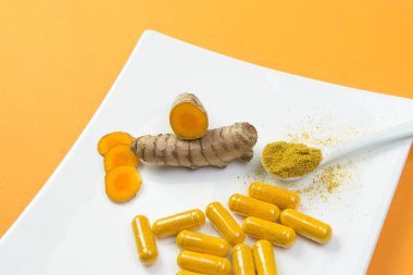 Beyaz plaka üzerinde zerdeçal kök ve curcuma kapsül