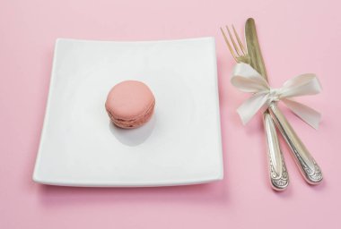 Beyaz tabak çatal ve pembe maracon, pembe bir arka plan ile 