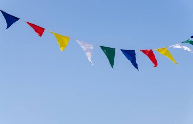 Mavi gökyüzünün önünde rüzgarda renkli bayraklar