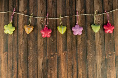 Bir kordon, ahşap arka plan ve kopyalama alanı üzerinde kalp ve çiçek şeklinde renkli dekorasyon kolye