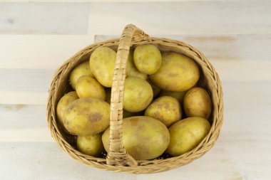 Tahta bir masanın üstünde duran patatesli sepet.