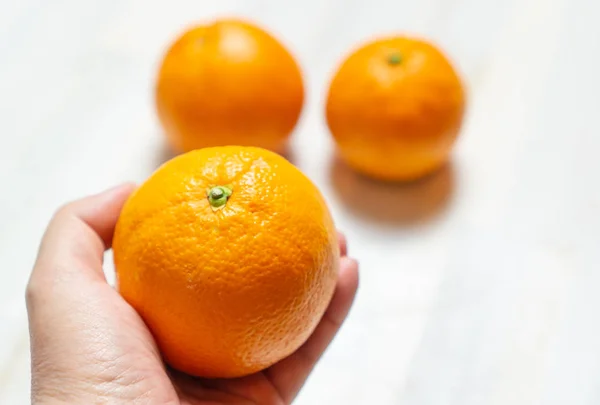 Woman holds an orange in the hand