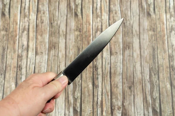 Butchers knife holding in hand, wooden background