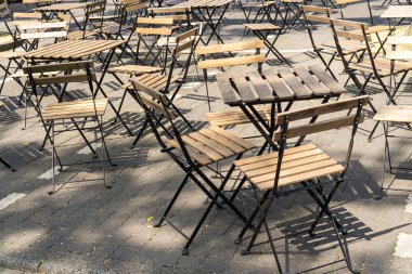 Parti başlamadan önce: güneşte boş ahşap masalar ve sandalyeler