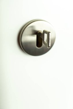 Beyaz bir kapıda yuvarlak gümüş anahtar deliğinde anahtar, kopyalama alanı