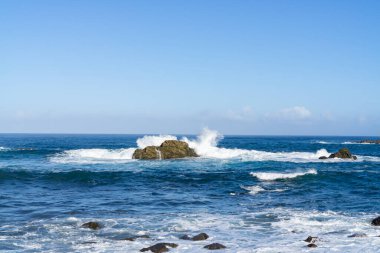 İspanya, Tenerife yakınlarındaki dalgalı Atlantik Okyanusu, sudaki kayalıklarda güçlü dalgalar kopuyor.