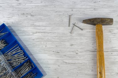 Çekiç ve beyaz ahşap zemin üzerinde çiviler olan mavi kutu, boşluğu kopyala