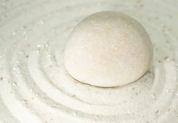 White stone in white sand, passing through the circles, copy space
