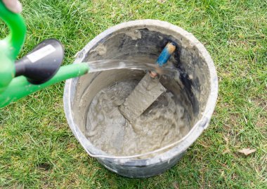 Su bidonu ile, su bir havan kovasına dökülüyor kova ve mala temizlemek için bir mala ile