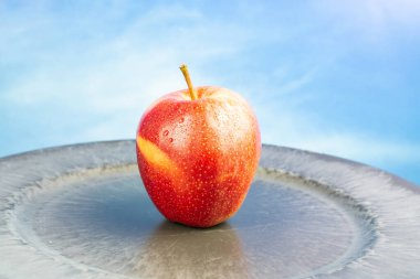 Su damlalı taze kırmızı elma meyvesi, mavi gökyüzü arkaplanı ve kopyalama alanı