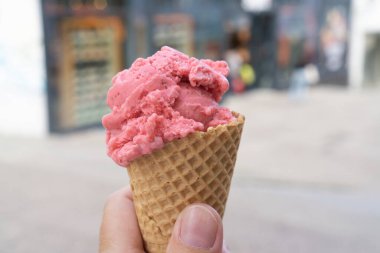 Elinde bir kepçe çilekli dondurma olan bir waffle.