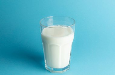 Mavi arka planda bir bardak taze süt, boşluğu kopyala