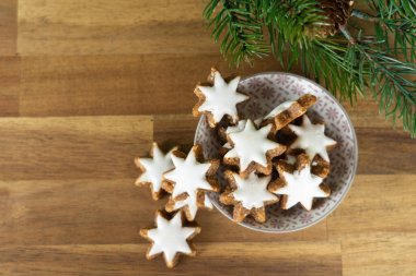 Tahta bir masanın üzerinde noel bisküvileri olan ve köknar dalları ve üst manzaralı bir fincan.