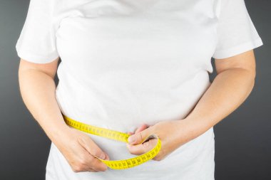 Kadının belinde bir mezura var.