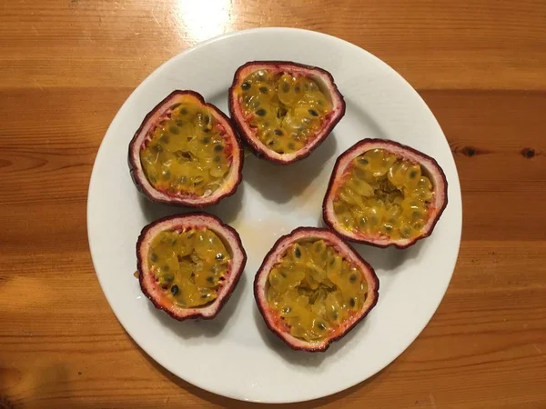 Fresh passion fruit cut in half on the plate on wood table in top view. — Stock Photo, Image