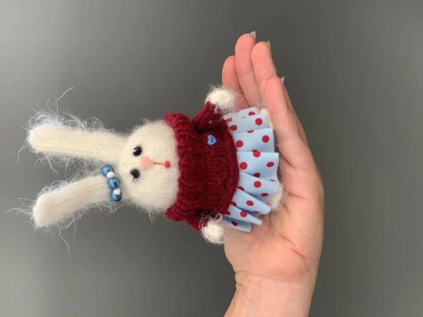 Hand made knitted toy rabbit or hare standing on the hand. Beautiful girl toy for children