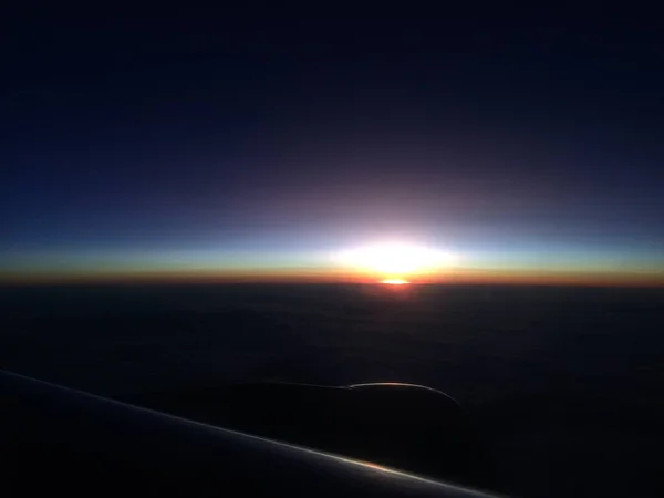 Vacker solnedgång eller soluppgång himmel ovanför moln med dramatiskt ljus. utsikt från flygplan — Stockfoto
