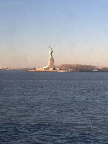 Minimale zeegezicht uitzicht op het standbeeld van Liberty silhouet in de horizon, brede blauwe en gele mistige hemel in de achtergrond, Staten Island, Manhattan, New York, Amerika, USA. — Stockfoto