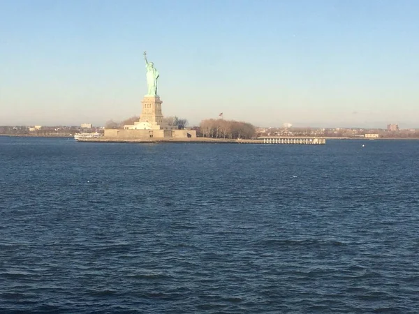 地平線の自由の女神のシルエットの最小限の海景、背景に広い青と黄色の霧の空、スタテン島、マンハッタン、ニューヨーク、アメリカ、アメリカ. — ストック写真