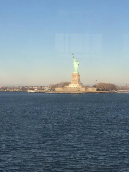 Minimaler Meerblick auf die Freiheitsstatue am Horizont, weiter blauer und gelber Nebelhimmel im Hintergrund, Staten Island, Manhattan, New York, Amerika, USA. — Stockfoto