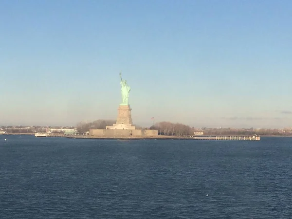 Minimale zeegezicht uitzicht op het standbeeld van Liberty silhouet in de horizon, brede blauwe en gele mistige hemel in de achtergrond, Staten Island, Manhattan, New York, Amerika, USA. — Stockfoto